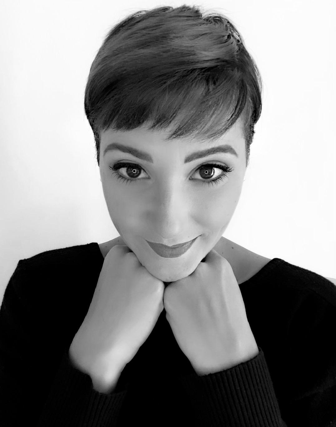 Ritratto in bianco e nero di Cristina Oddo, capelli corti e mento appoggiato sulle mani